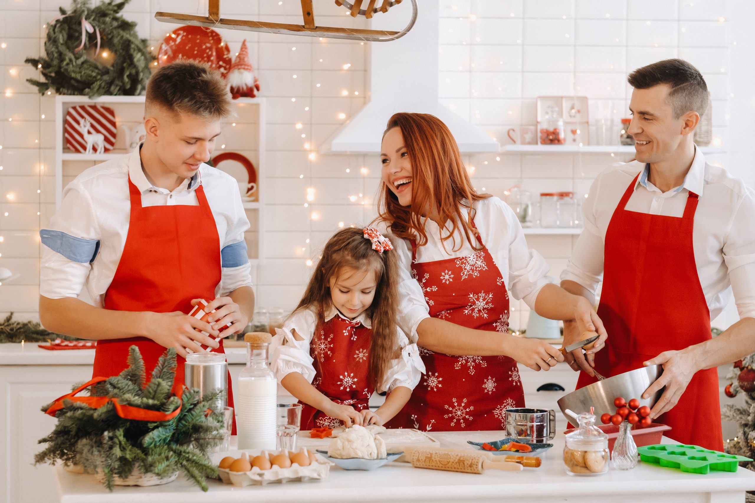 A happy family is standing in the Christmas kitchen and preparing dough for making cookies