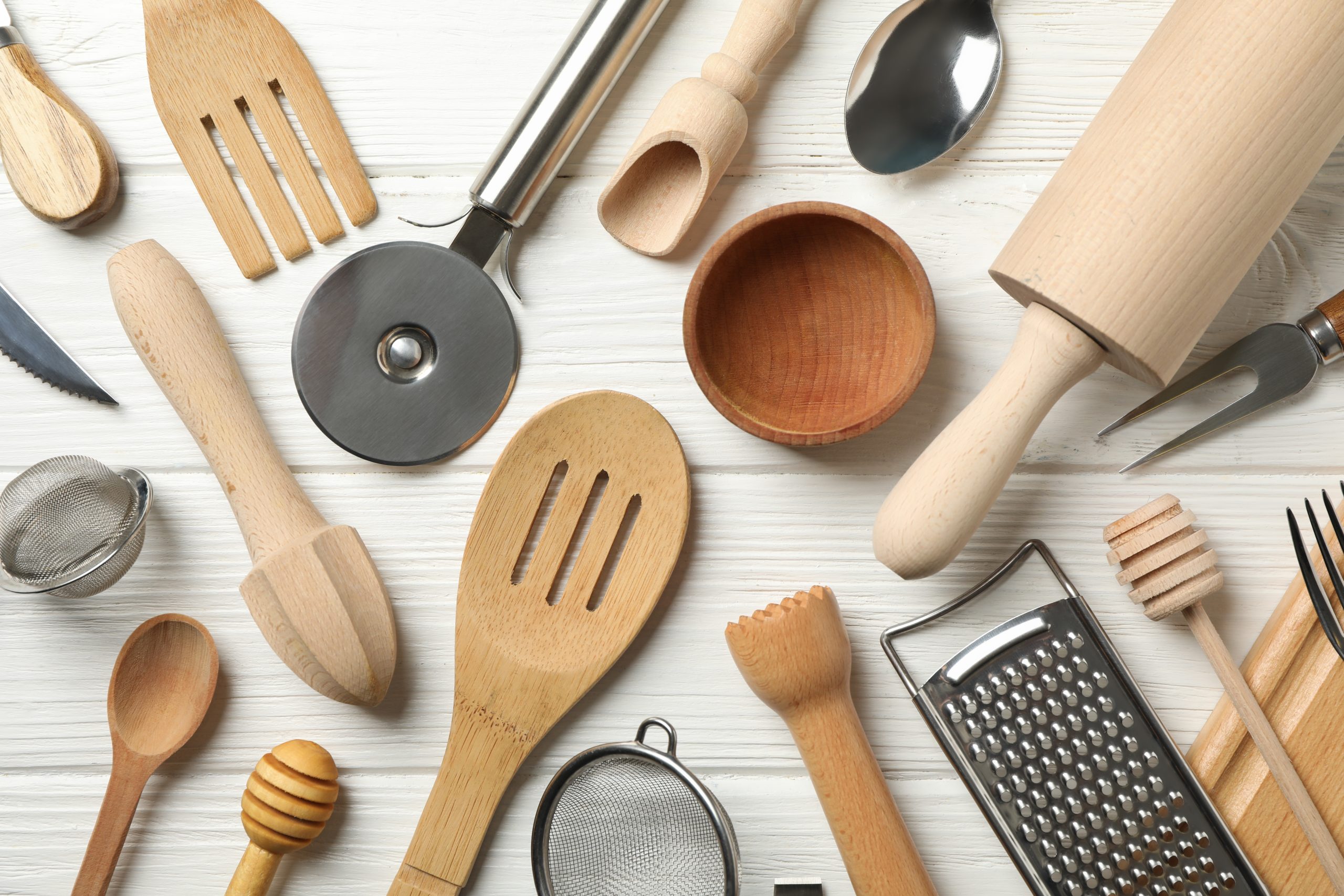 Different kitchen cutlery on white wooden background